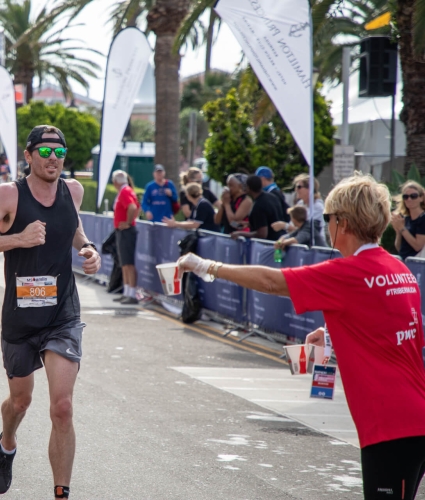 Volunteer passes runner water during triathlon in Bermuda