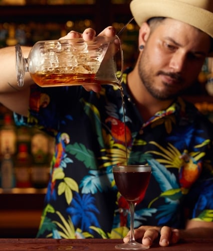 A man is pouring a cocktail into a glass.