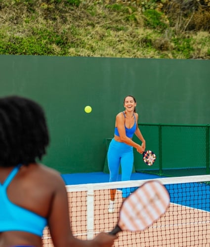 Two women are playing pickleball.