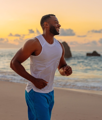 A man is running on the beach smiling.