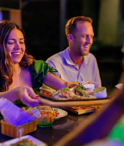 A woman is passing a plate of food around.