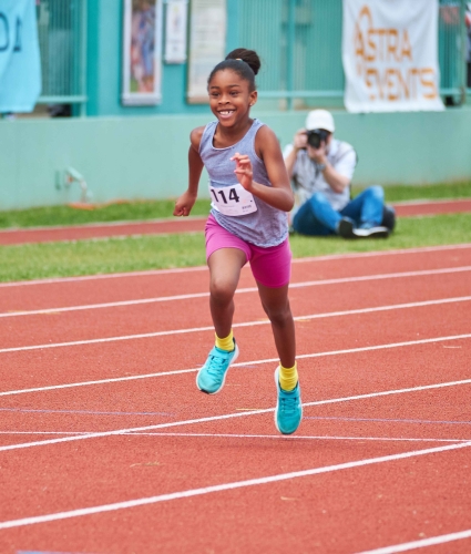 A little girl is running on the track.