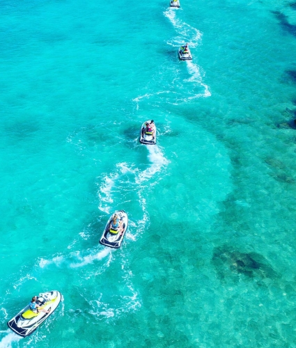 A convoy of sea-doos riding on turquoise water