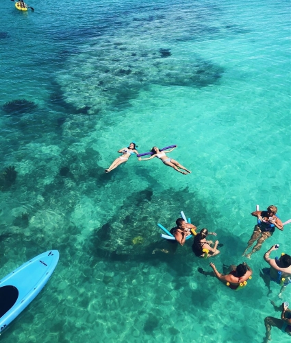 A group of people with floatation devices hanging out in the ocean