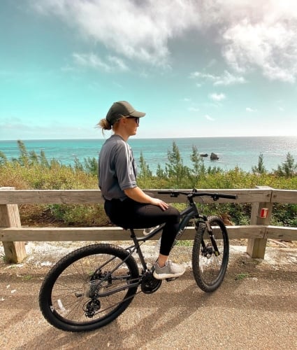 A bicycle rider pauses to admire panoramic ocean views in Bermuda.