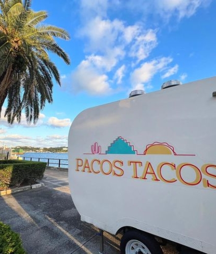 Paco's Tacos truck parked near water and palm trees.