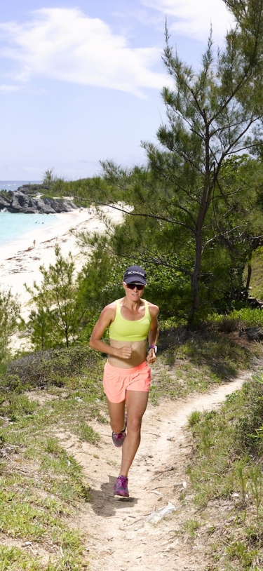 A woman running through Bermuda on a hiking trail