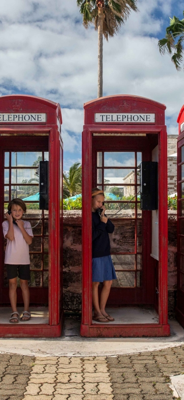 A family is standing in old British style telephone booths.