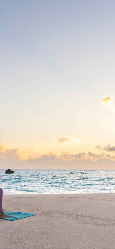 A woman is doing a yoga pose on the beach.