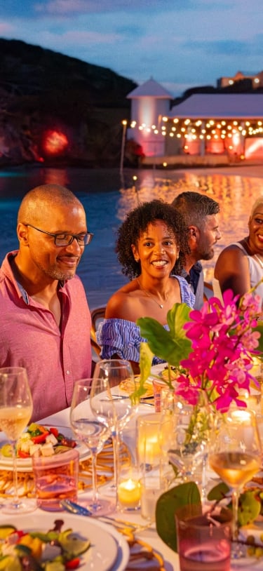 A group is smiling at dinner table.