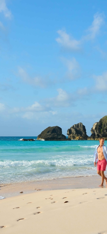 A man and woman are walking along an empty beach.