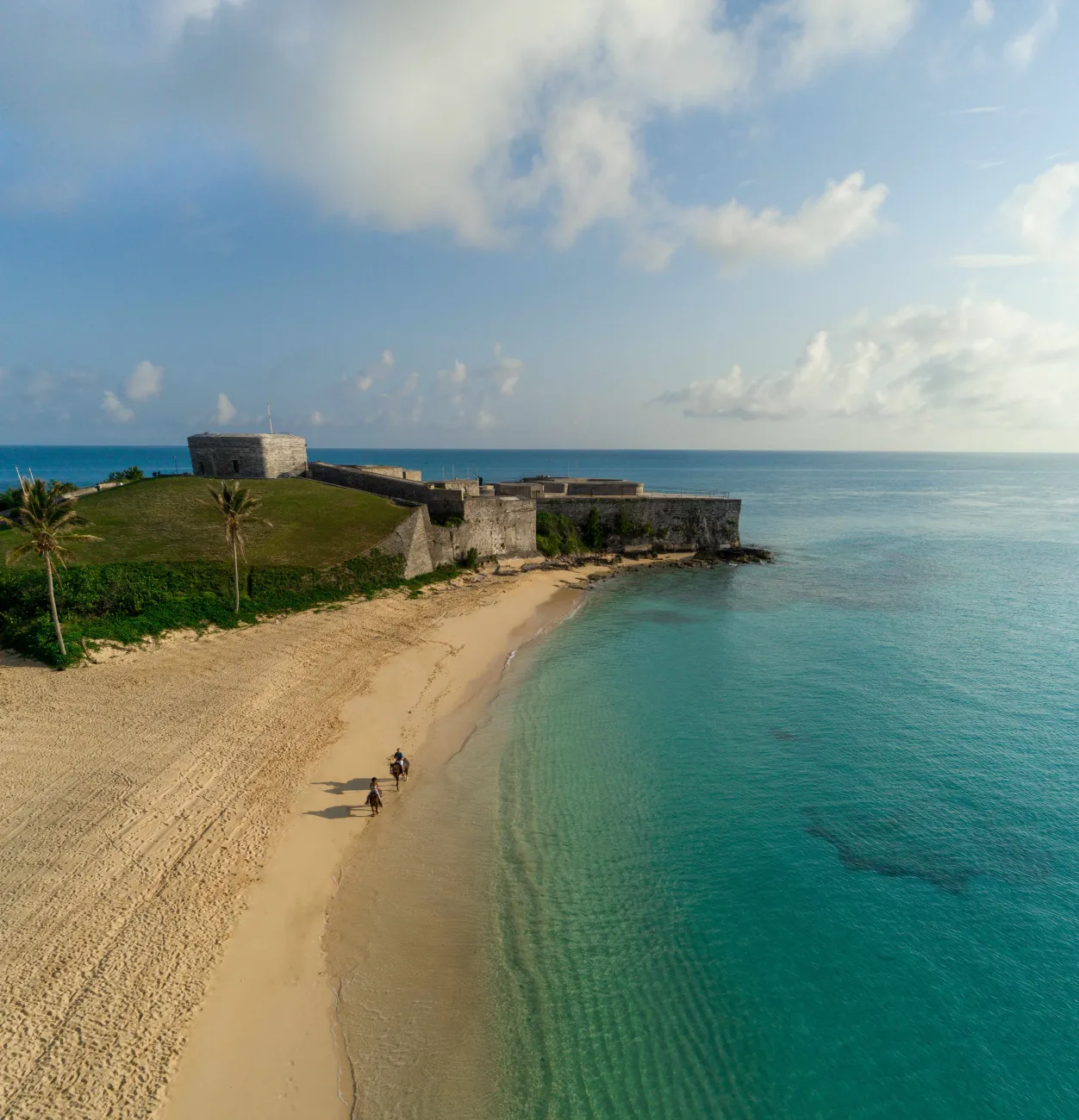 The fort at Tobacco Bay, overlooking two people riding horses on the beach