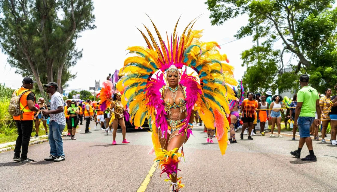A woman in an elaborate colourful feathery outfit poses on the street during carnival in Bermuda