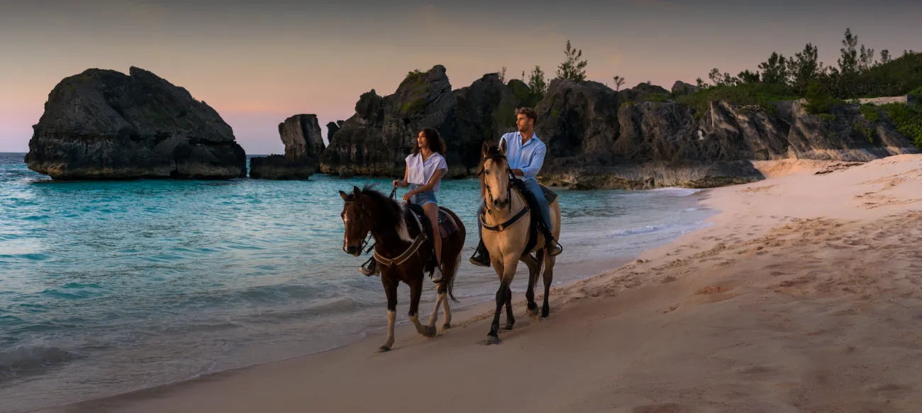 A couple horseback riding on the beach