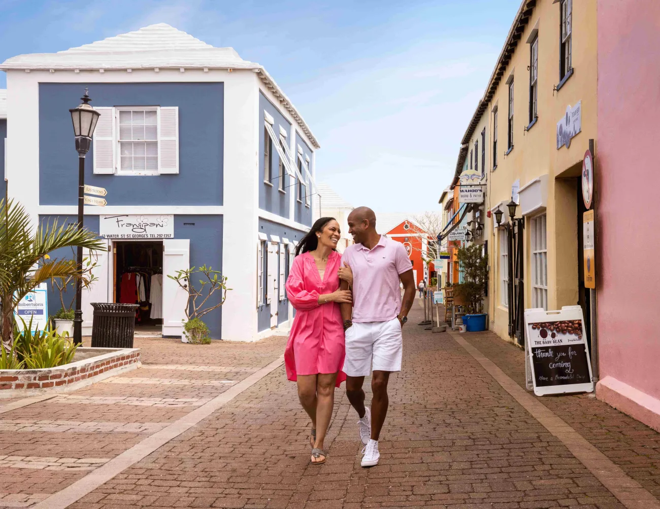 A couple walking arm in arm down a street in St. George's