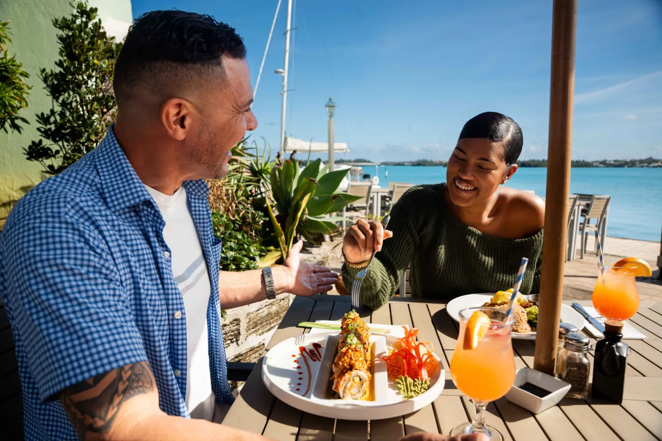 A couple are enjoying lunch at The Wharf by the water.