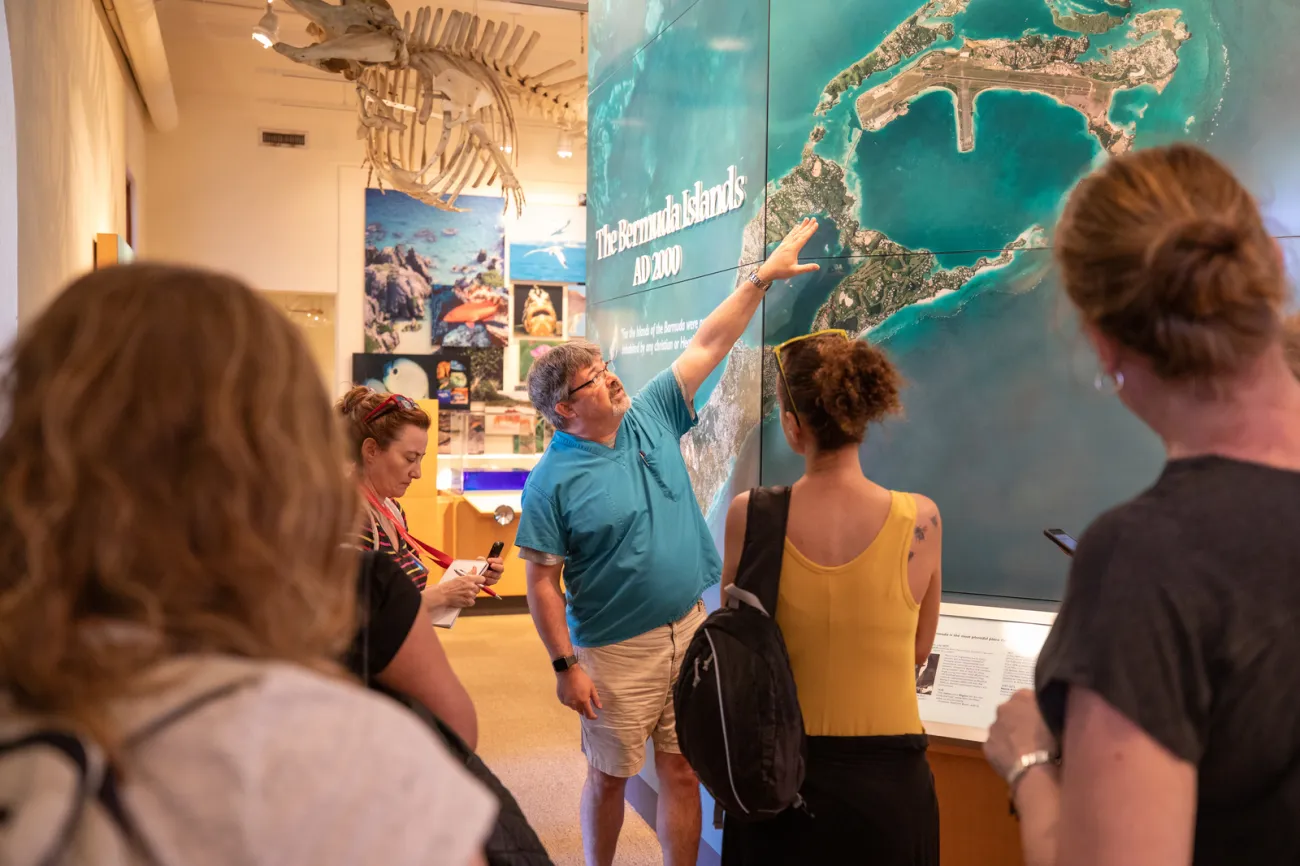 A man is showing people a map of the Bermuda Islands.