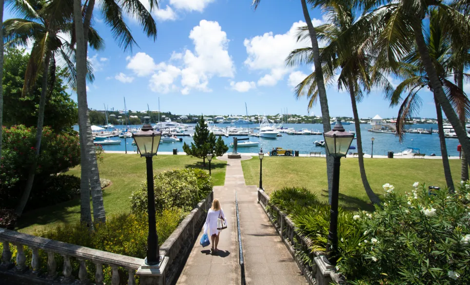 Woman walks down a path towards a yacht dock yard
