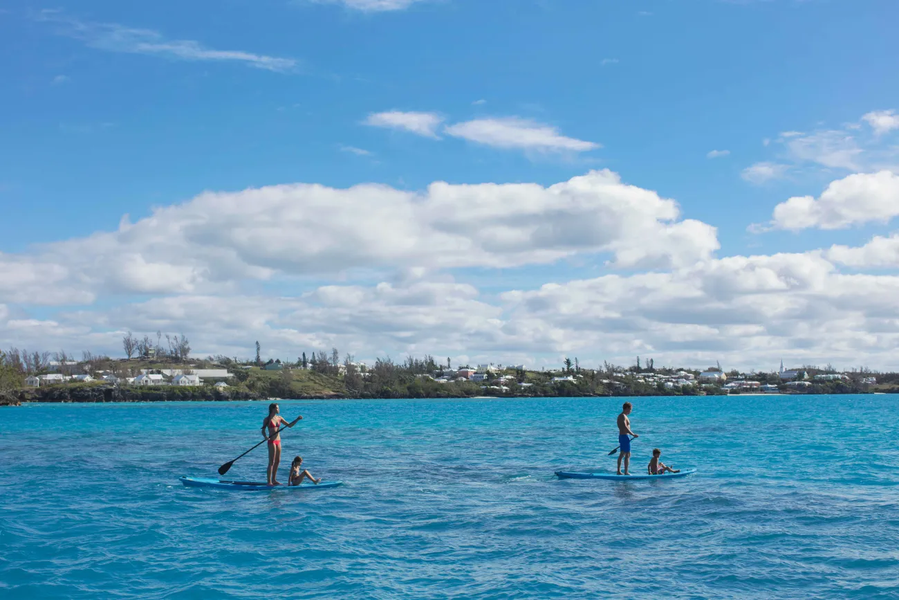 A couple is paddle boarding with their children.