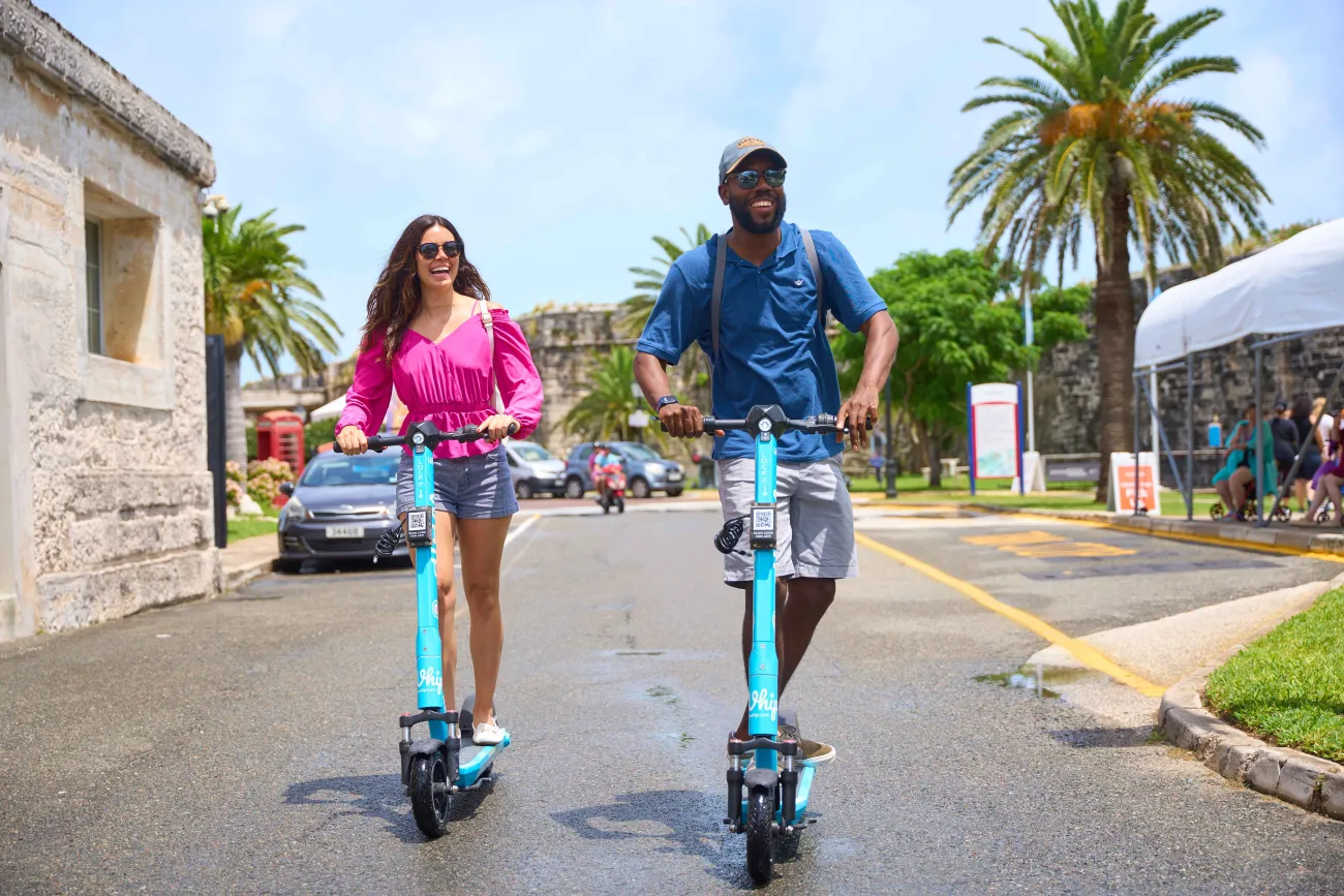 A man and a woman are riding electric scooters. 