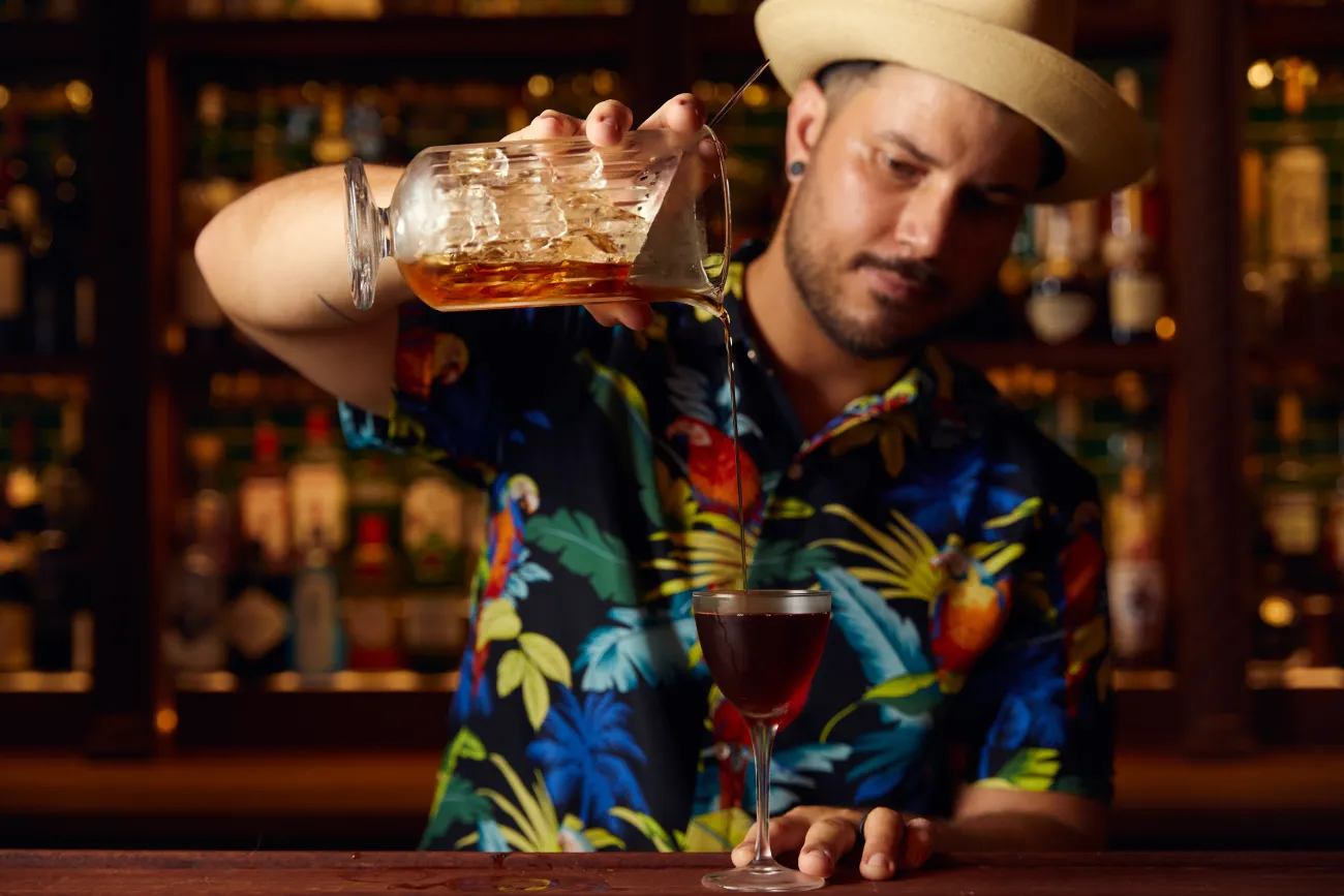 A man is pouring a cocktail into a glass.