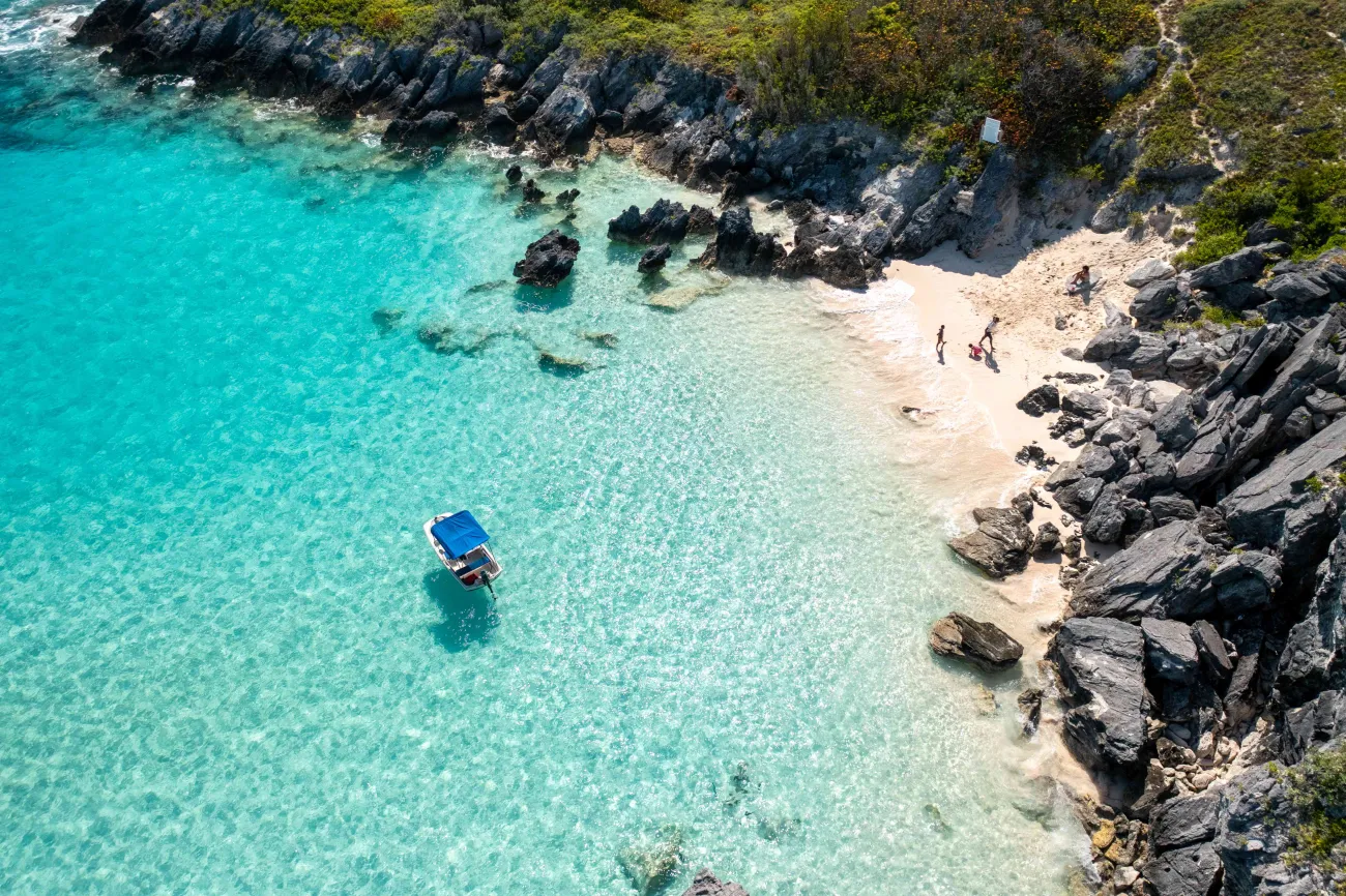 A family is on the beach with a boat floating in the distance.
