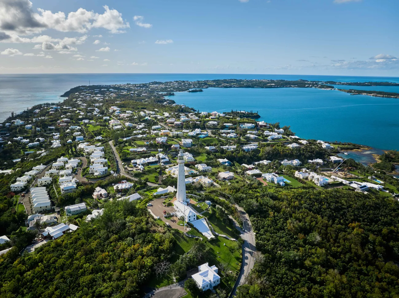 Aerial view of Gibbs Hill Lighthouse with calm waters and blue skies. 
