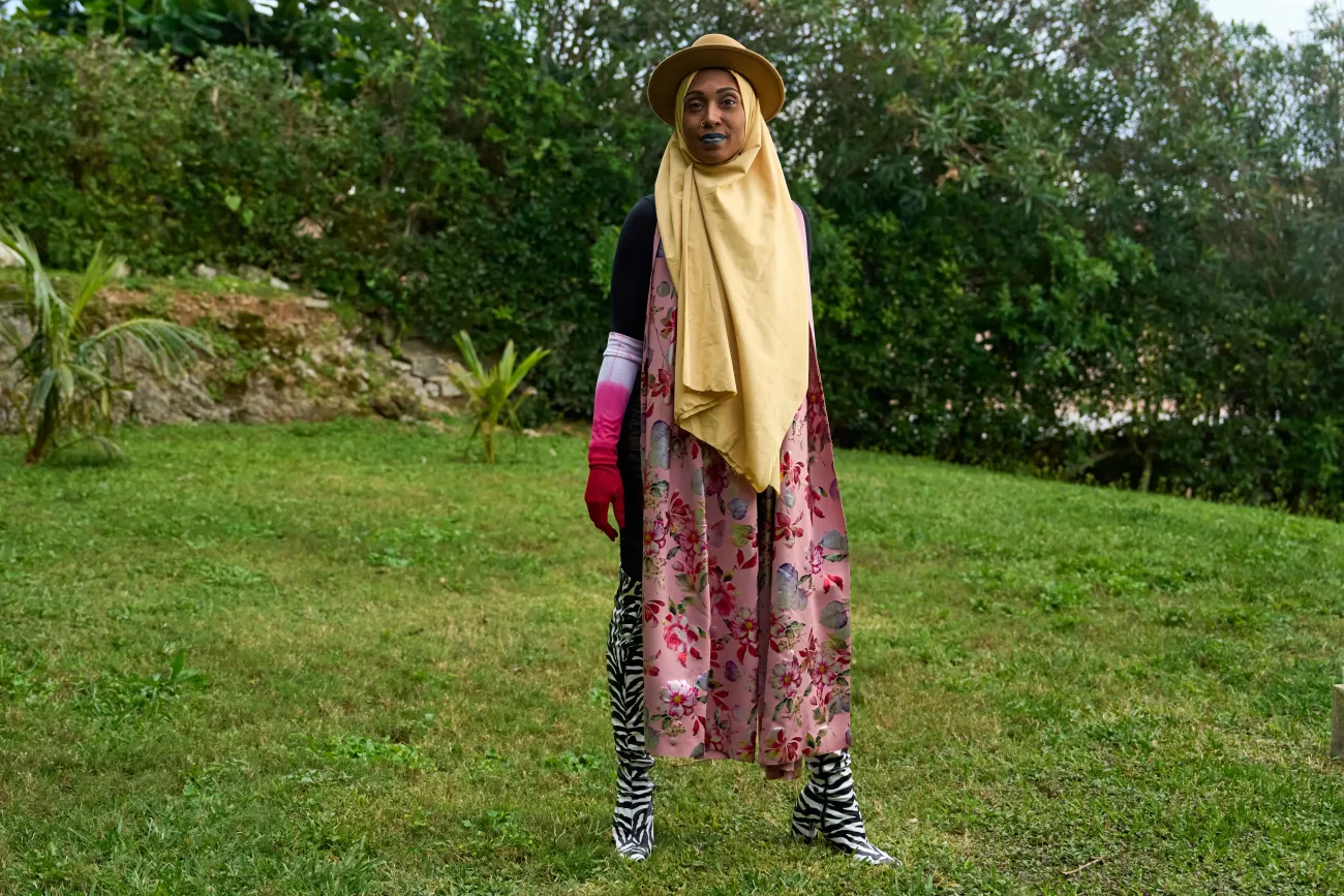 A woman is standing in a colourful outfit on the grass.