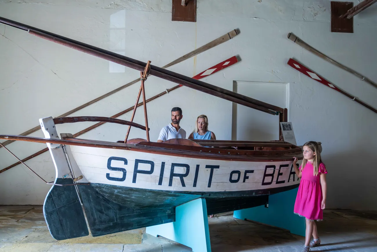 A family are standing by a n old historic boat