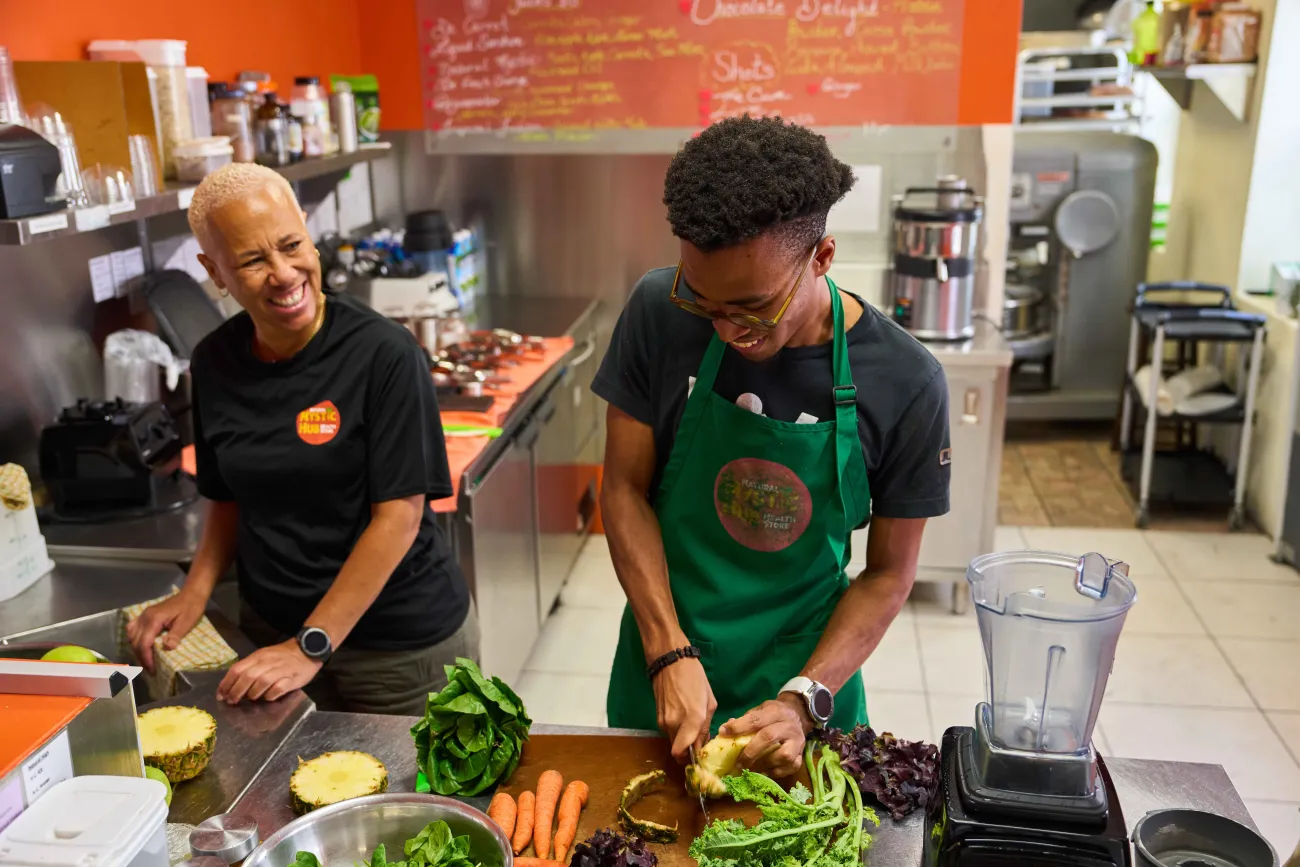 An older woman and young man are cooking in a kitchen.