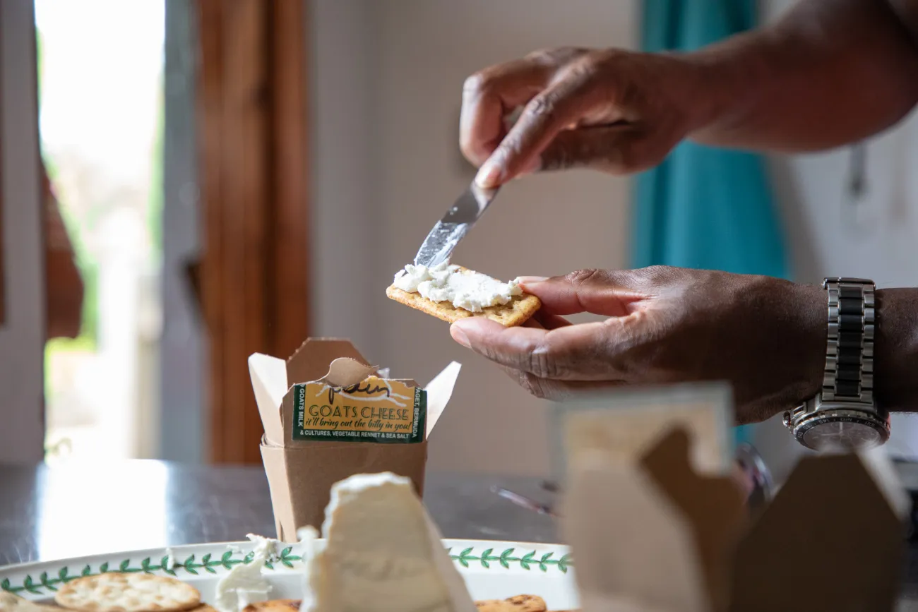 A person is spreading goat cheese on a cracker.