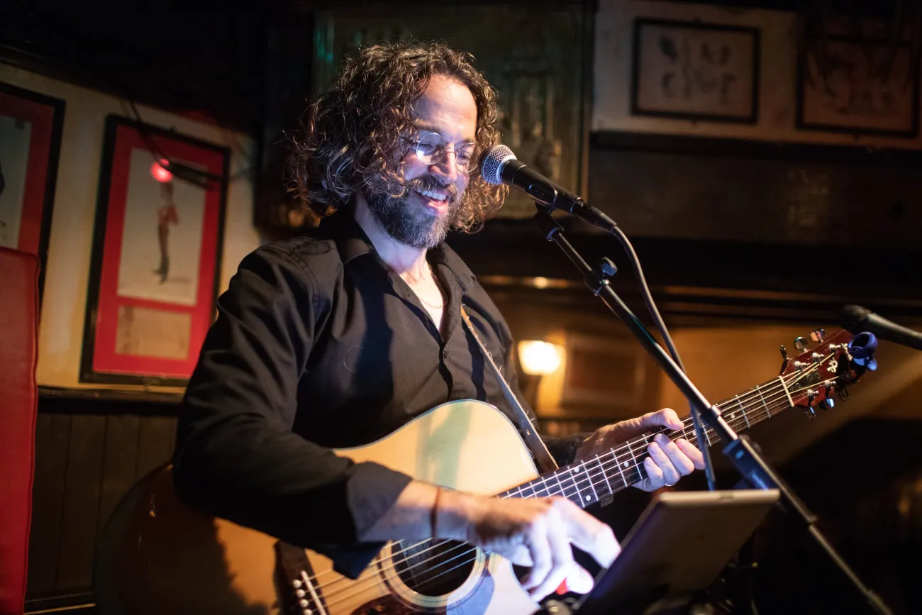 A man is playing a guitar and singing in the mic.