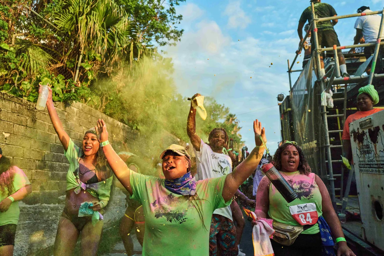 A group of people are smiling while paint is being thrown every where.