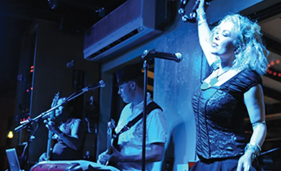 A three piece band plays with a guitar and tamborine