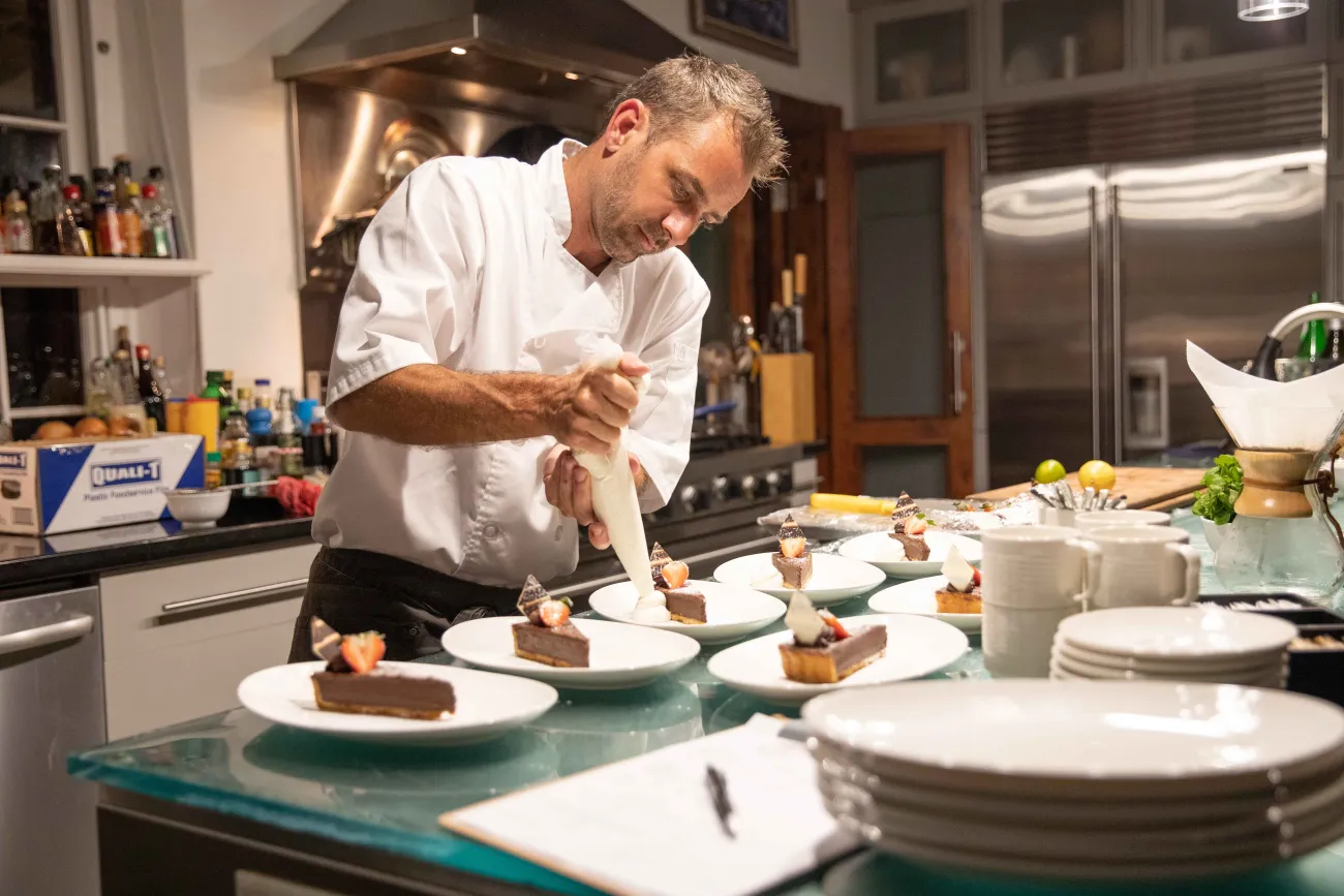 A chef is preparing plates during a private dinner.