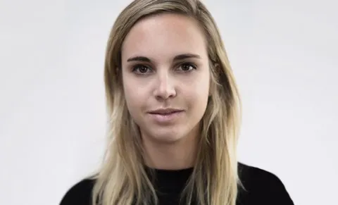 Headshot of a woman with blonde hair and black shirt slightly smiles at the camera
