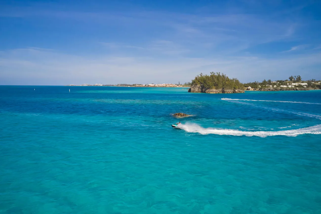 Two people are jetskiing by a shipwreck.