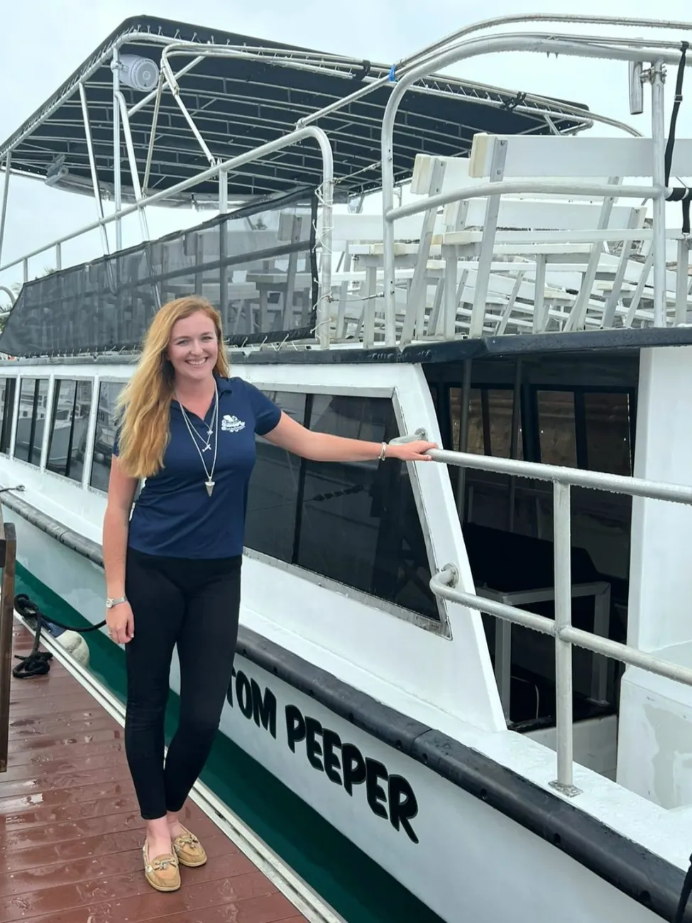 A woman is smiling at the camera by a boat.