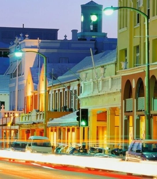 Street view at night with cars parked on the side of the road