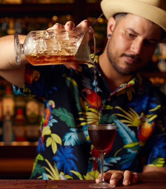 A man is pouring a cocktail into a glass.