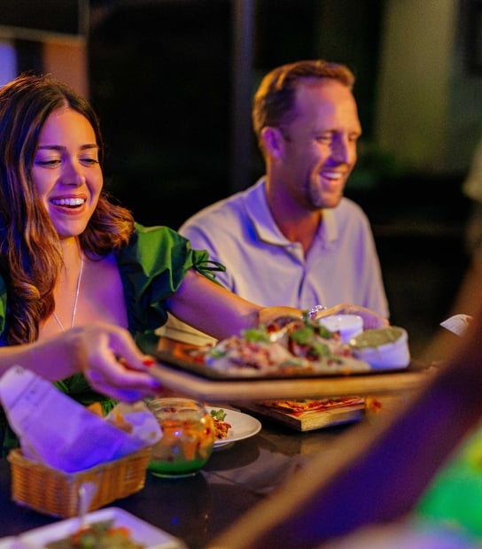 A woman is passing a plate of food around.