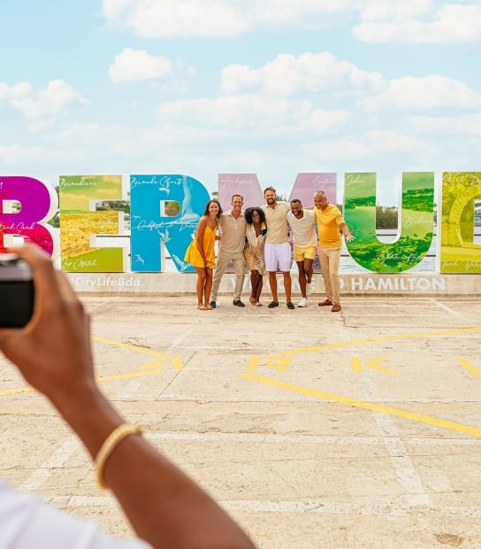 People posing by the Bermuda sign.