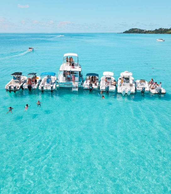 A group of boats and swimmers all together on the turquoise blue waters of Bermuda