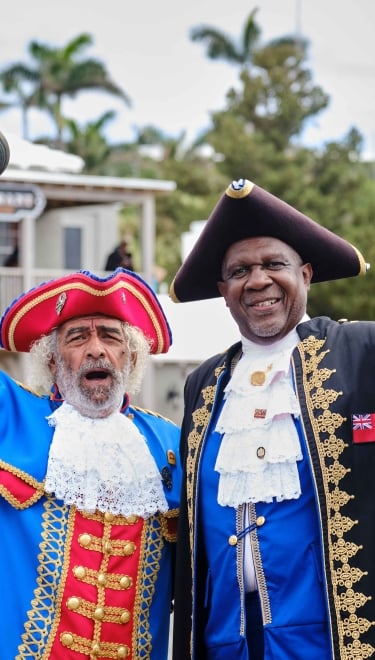 Bermudian tour guides in historical regalia welcome visitors.