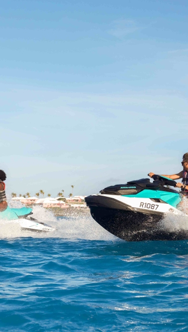 Two people are jetskiing on a clear day.