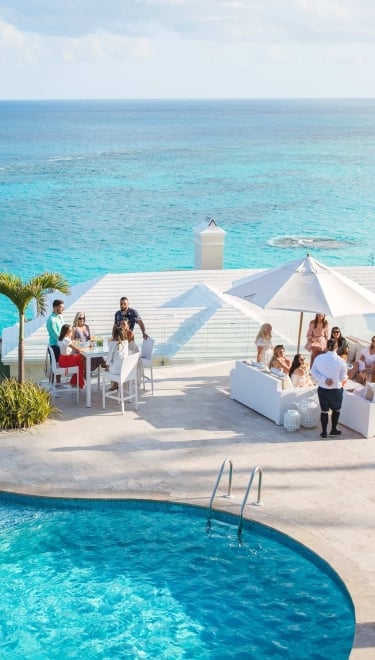 A group are sitting at a viewpoint with the ocean in the background.
