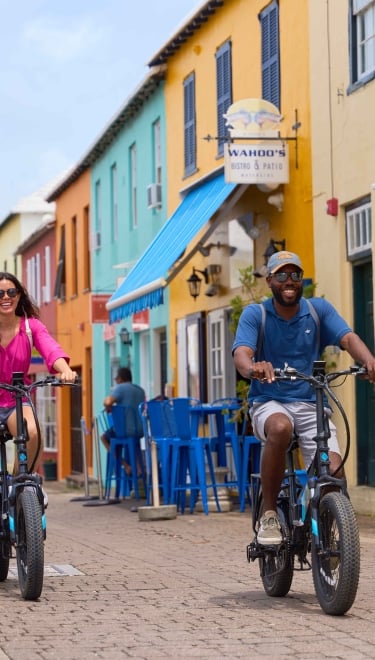 Two people are riding electric vehicles through St. George's