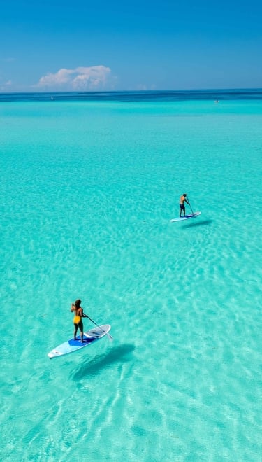 two people paddleboarding with clear waters.