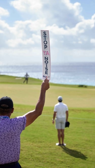 A man is holding a quiet sign at the Butterfield Bermuda Championship.