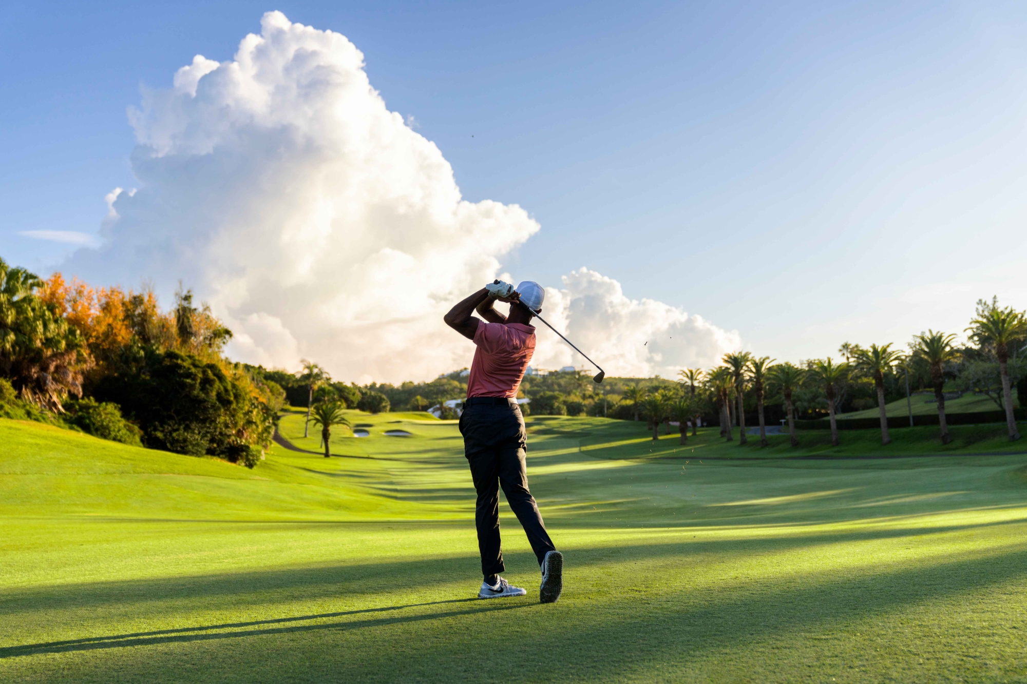 A man is hitting a golf ball on a golf course. 